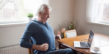 Man exercising while sat in a chair at the table