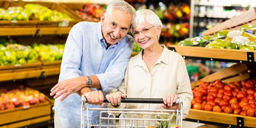 Older Couple Shopping Together In The Fruit And Veg Aisle Of A Supermarket