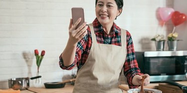 Woman baking while making a video call on her mobile