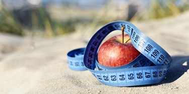 Apple on sand with measuring tape