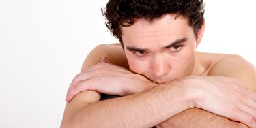 Man Sat Up With Crossed Arms Looking Concerned