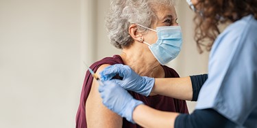 Woman receiving vaccine by medical professional